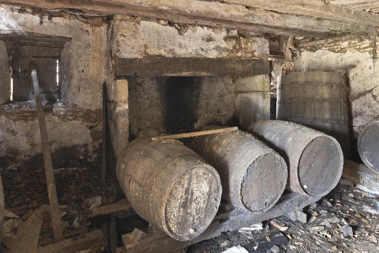 Vue intérieure de la cabane de vigneron : barriques sur leur chantier et cuve en bois.