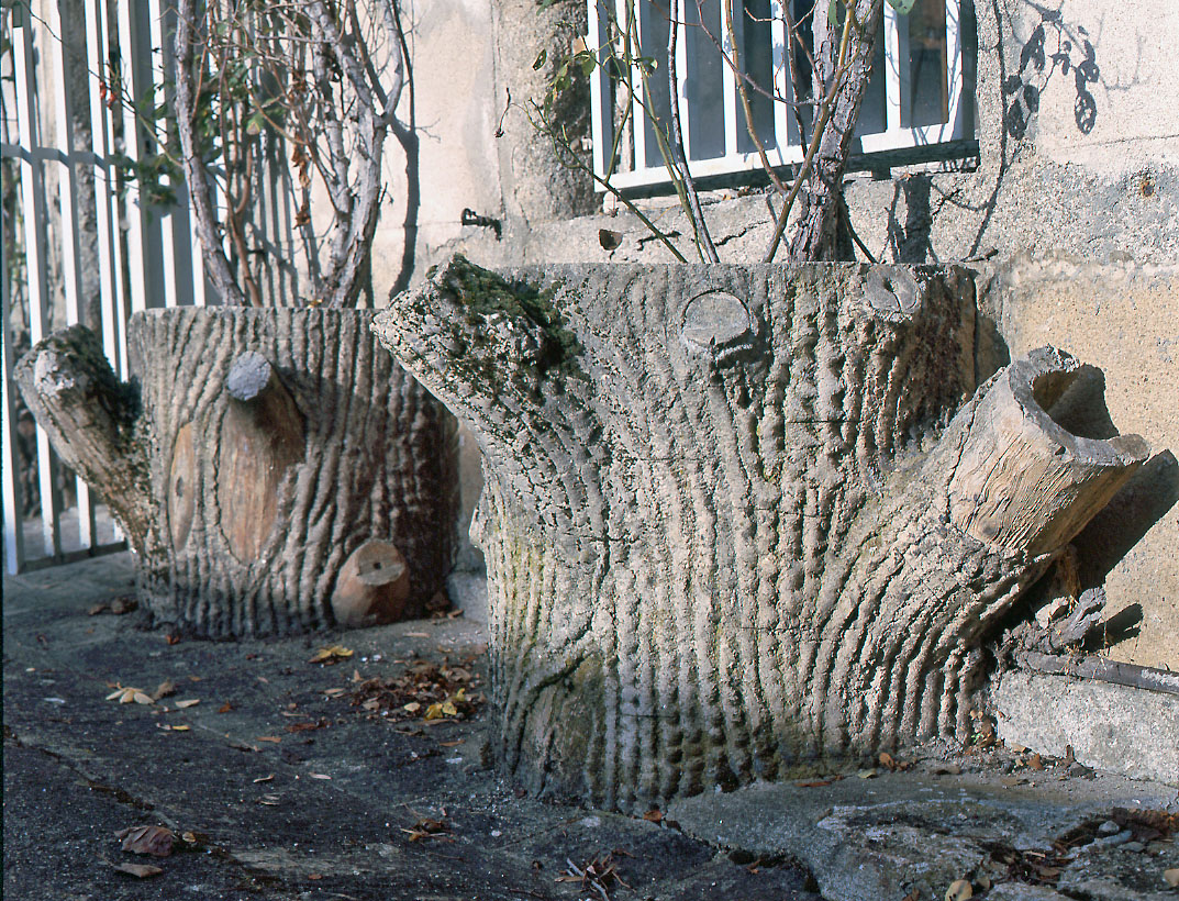 Détail, dans la cour : deux pots de fleurs en forme de troncs d'arbre, réalisés dans la technique de la rocaille