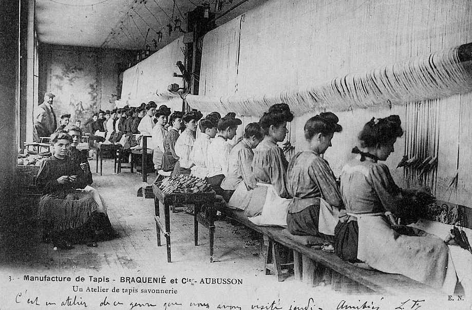Carte postale (1er quart 20e siècle) : un atelier de tissage de tapis Savonnerie de la manufacture Braquenié, avec les ouvrières au travail (collection particulière)
