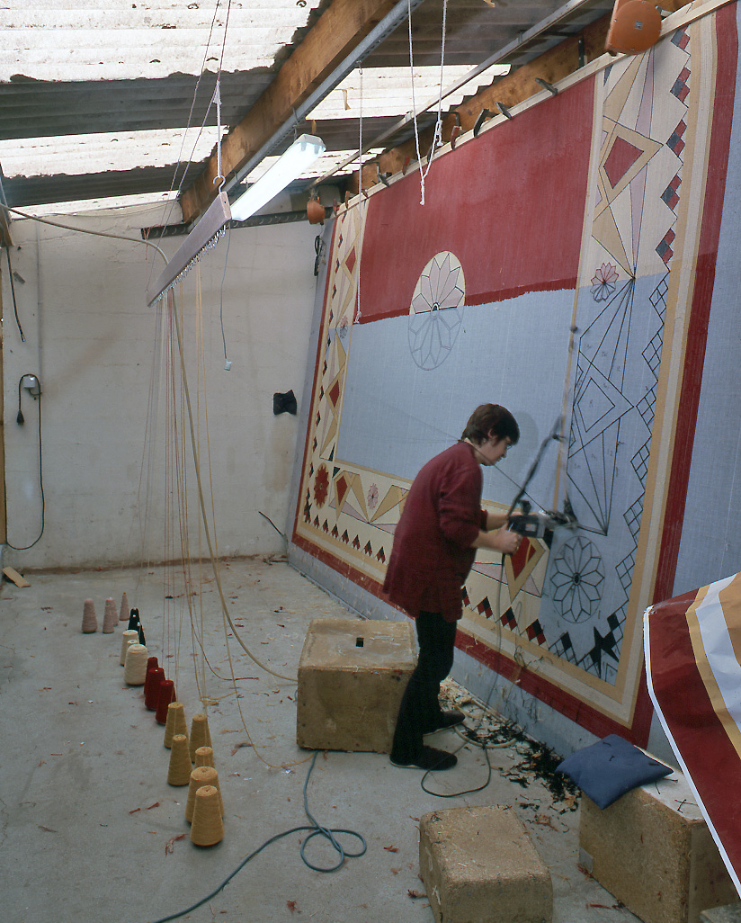 Vue intérieure de l'atelier de tissage au point piqué main, avec un tapis en cours de réalisation, à l'aide d'un pistolet à air comprimé.