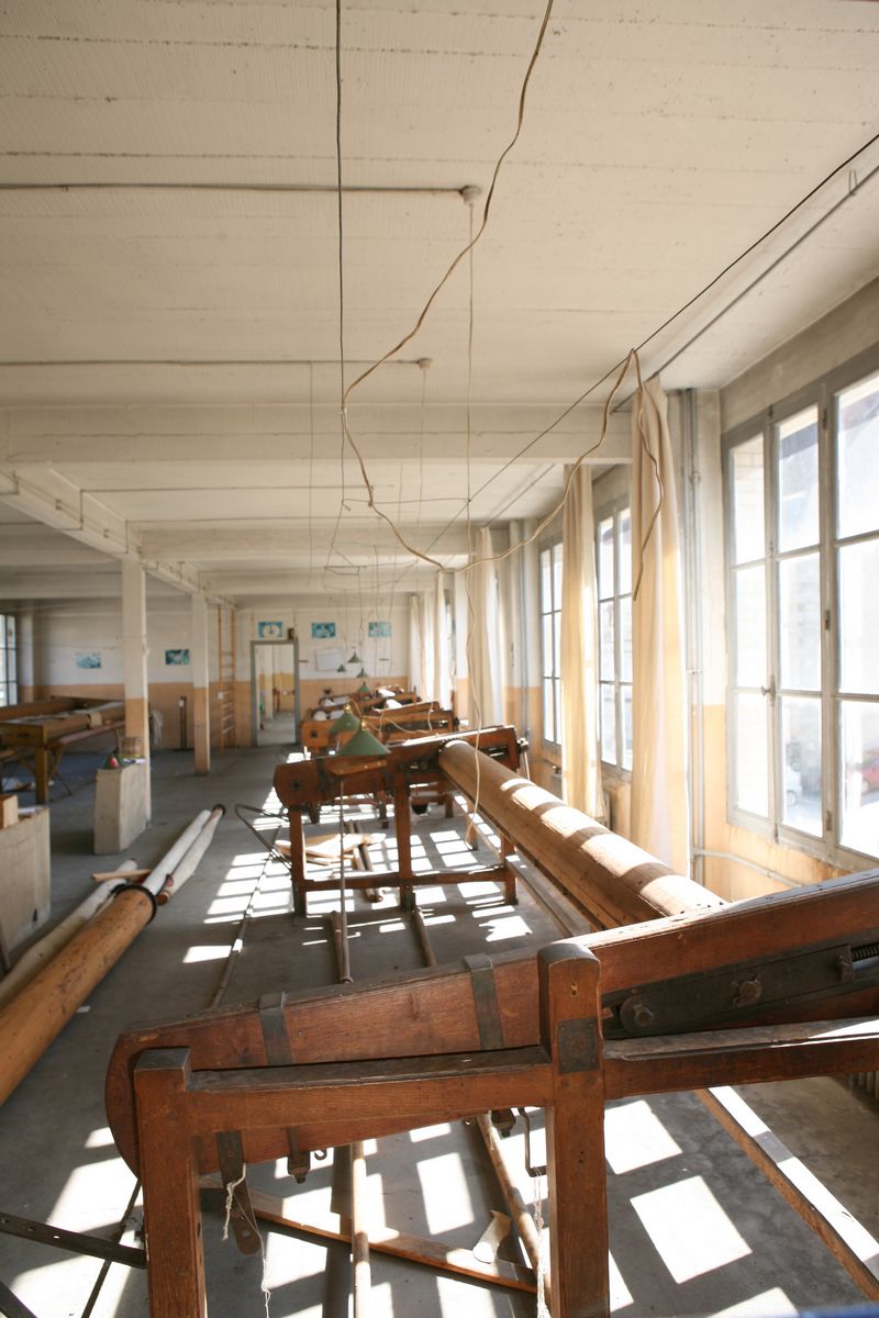 Vue générale de l'atelier de tissage en basse lisse, situé au premier étage du bâtiment édifié en fond de cour, parallèlement à la Beauze.