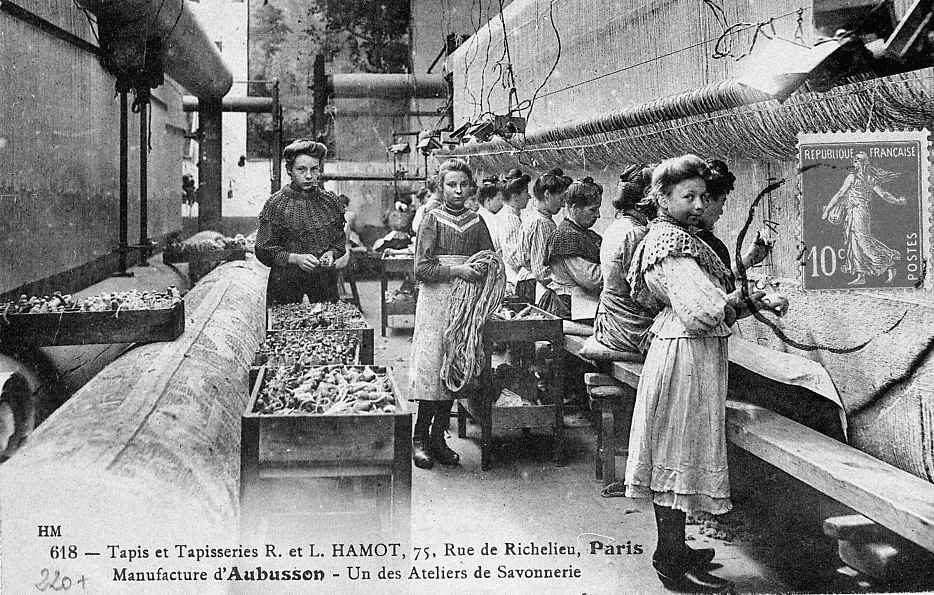 Carte postale (1er quart 20e siècle) d'un atelier de tissage de tapis Savonnerie de la manufacture Hamot, avec les ouvrières au traval, aidées par des enfants (collection particulière)
