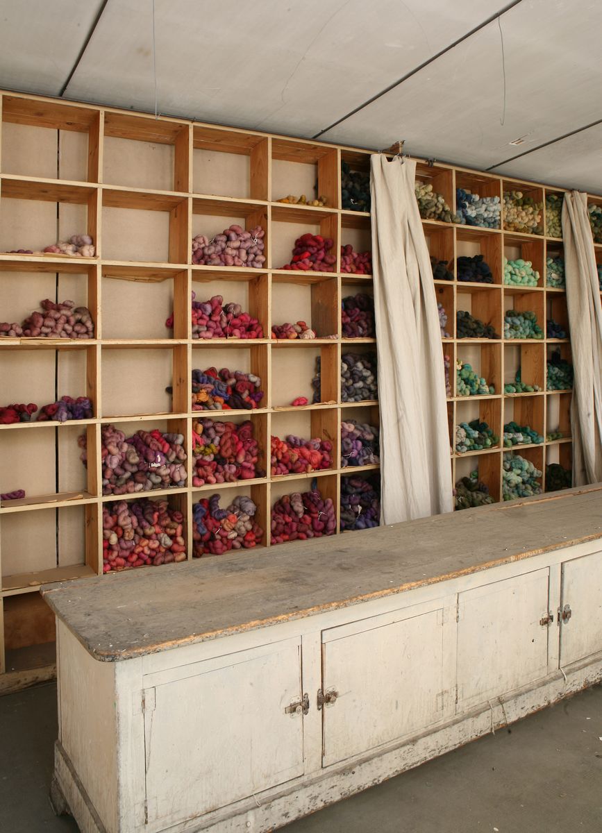 Détail des casiers contenant les écheveaux de laine vierge, rangés par nuances de couleur, dans le magasin des laines, au second étage.