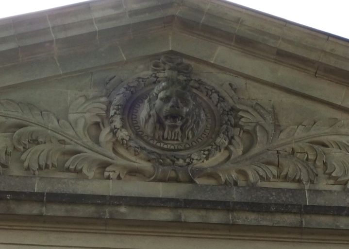 La tête de lion sculptée sur le fronton de la façade nord-ouest du logis.