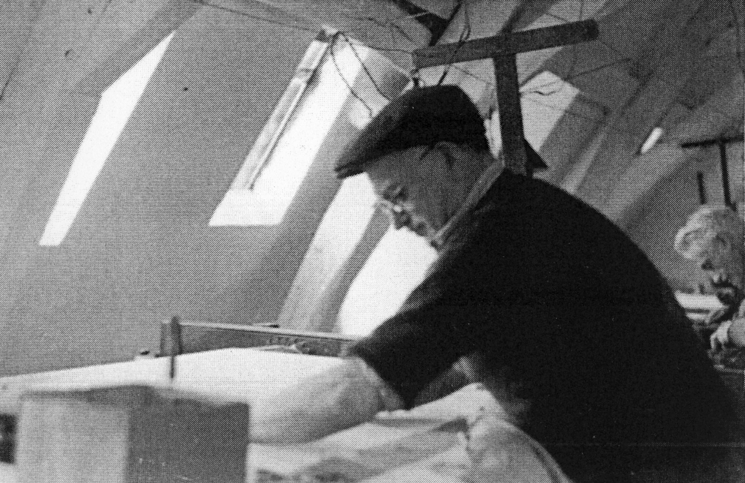 Vue d'un ouvrier au travail, tissant sur un métier à barre de l'atelier installé dans les combles (v. 1970).