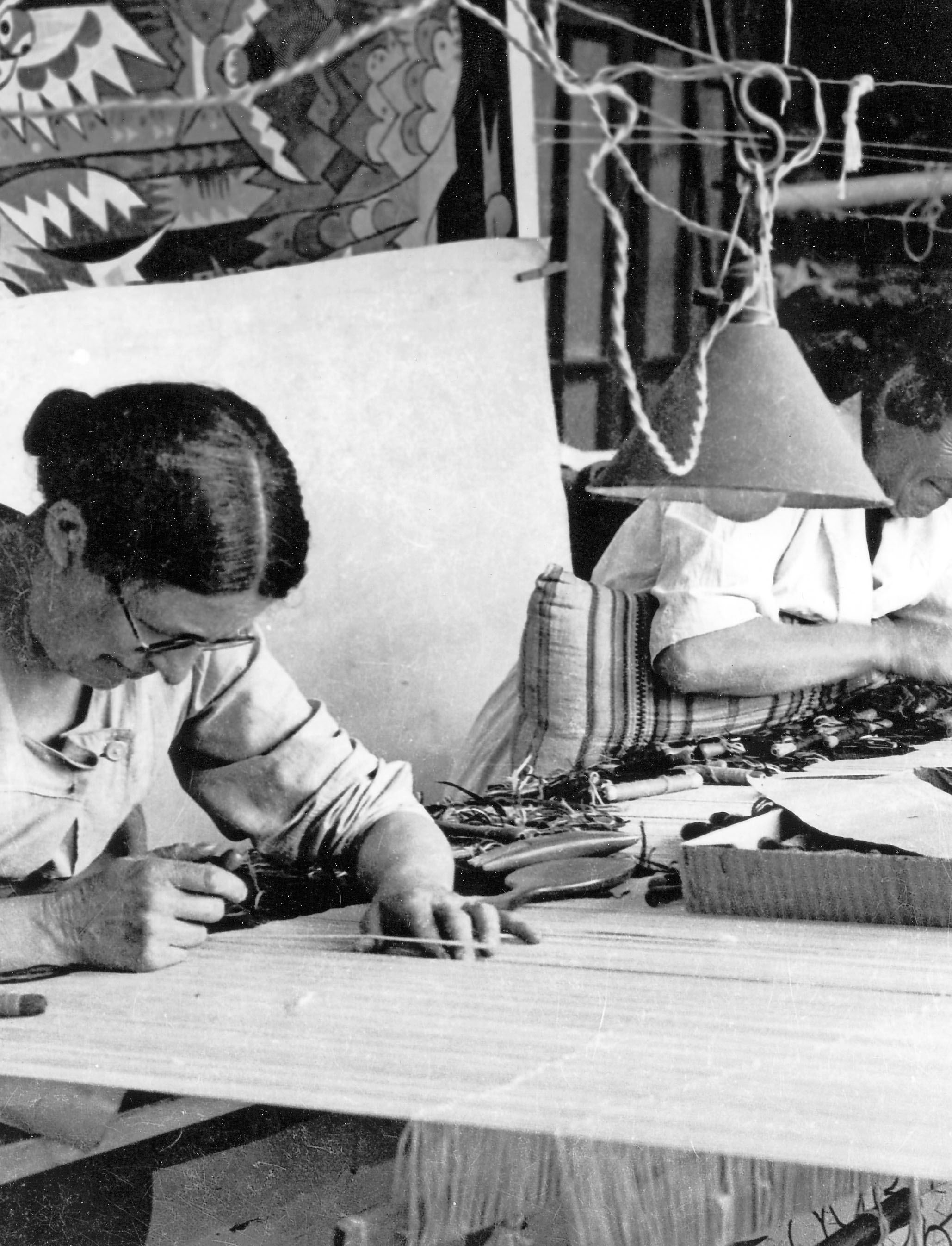 Vue d'une ouvrière au travail, dans l'atelier de tissage de la manufacture Goubely (v. 1970).