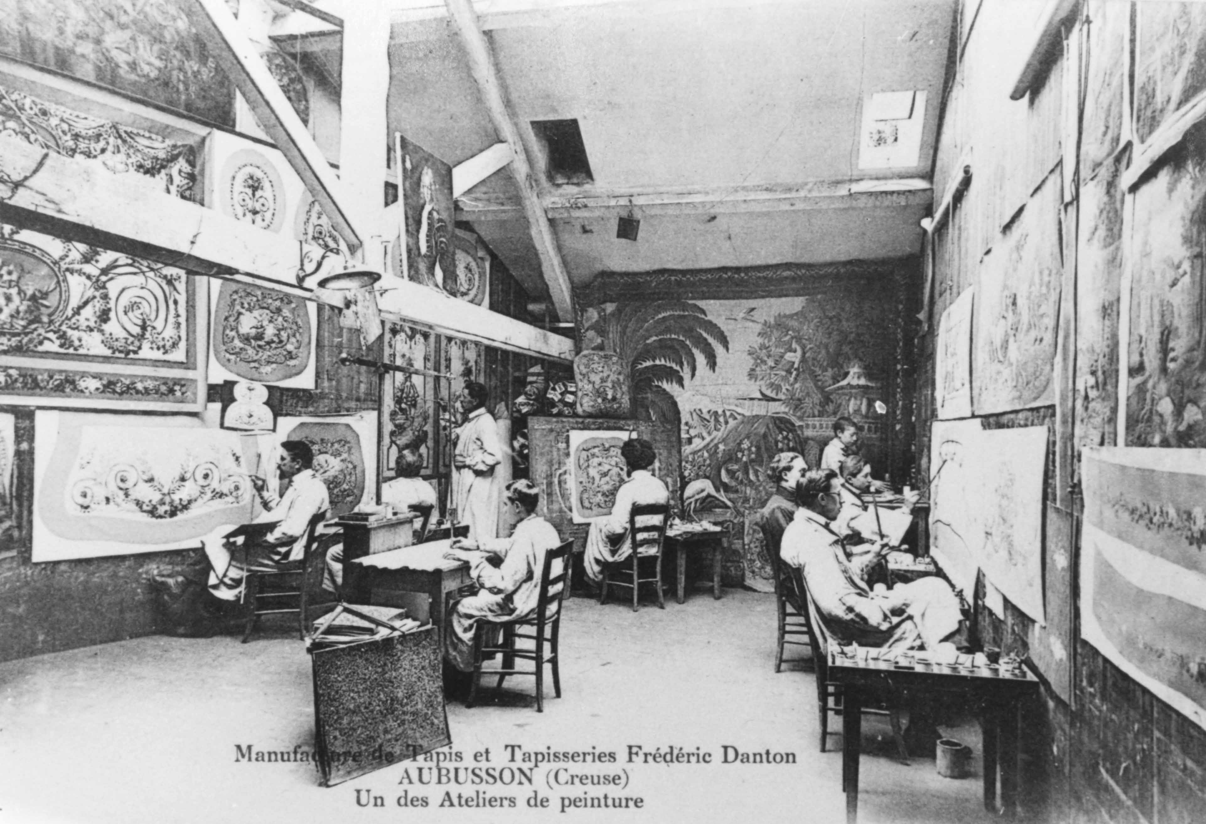 Carte postale (1er quart du 20e siècle) d'un atelier de peinture de la manufacture Danton, avec les cartonniers au travail (Aubusson, centre de documentation du Musée départemental de la Tapisserie)