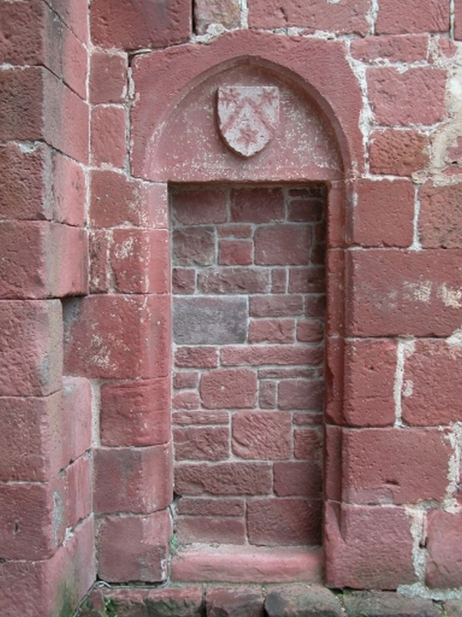Vue de la porte murée située sur l'élévation sud et surmontée d'un écu portant les armes de la famille de Maussac.