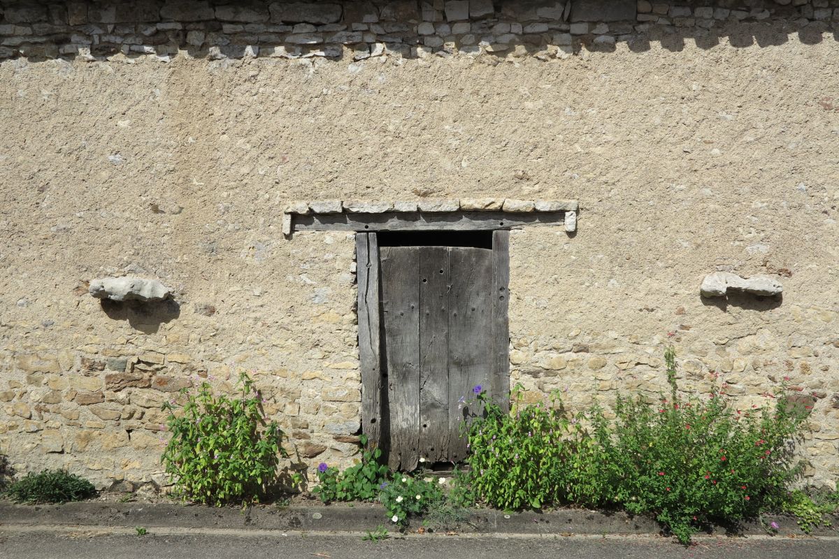 Grange à Mortioux, porte d'accès à l'étable, à encadrement en bois et linteau protégé par un larmier en pierre. Elle est encadrée d'anneaux à attacher les animaux.