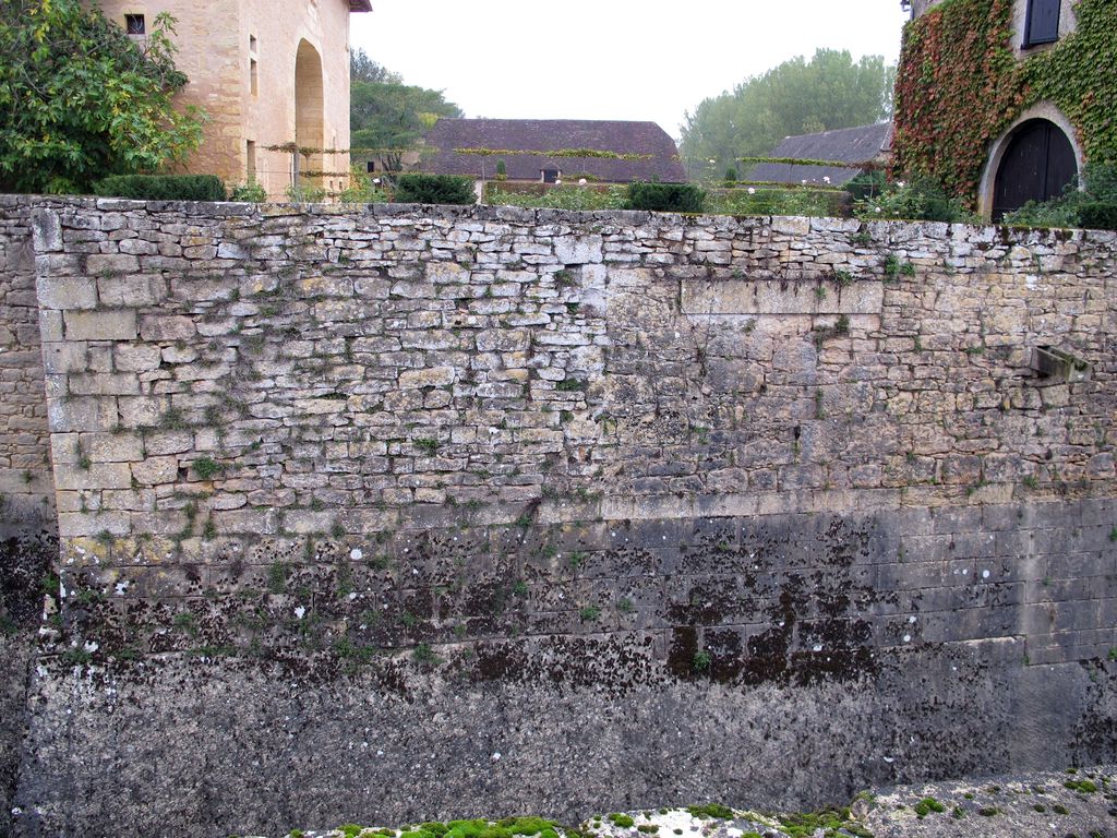 Détail du mur d'escarpe sud de la plate-forme du château : rocher taillé et assises en pierre de taille surmontées d'une maçonnerie plus récente, avec l'allège d'une fenêtre disparue.