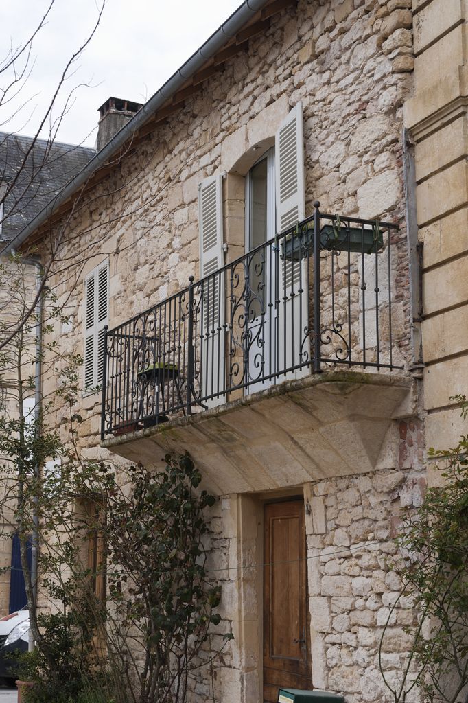 Maison du XIXe siècle de Montignac : détail du balcon du premier étage en pierre de taille muni d'un garde-corps en fer.