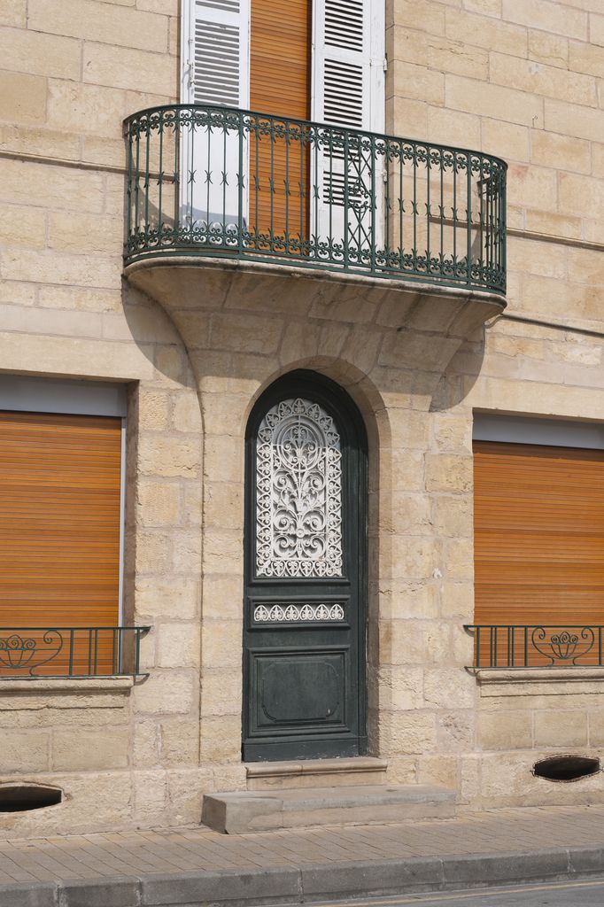 Détail de la porte d'entrée en plein-cintre d'une maison du XIXe siècle de Montignac ; balcon en pierre portant un garde-corps en fer.