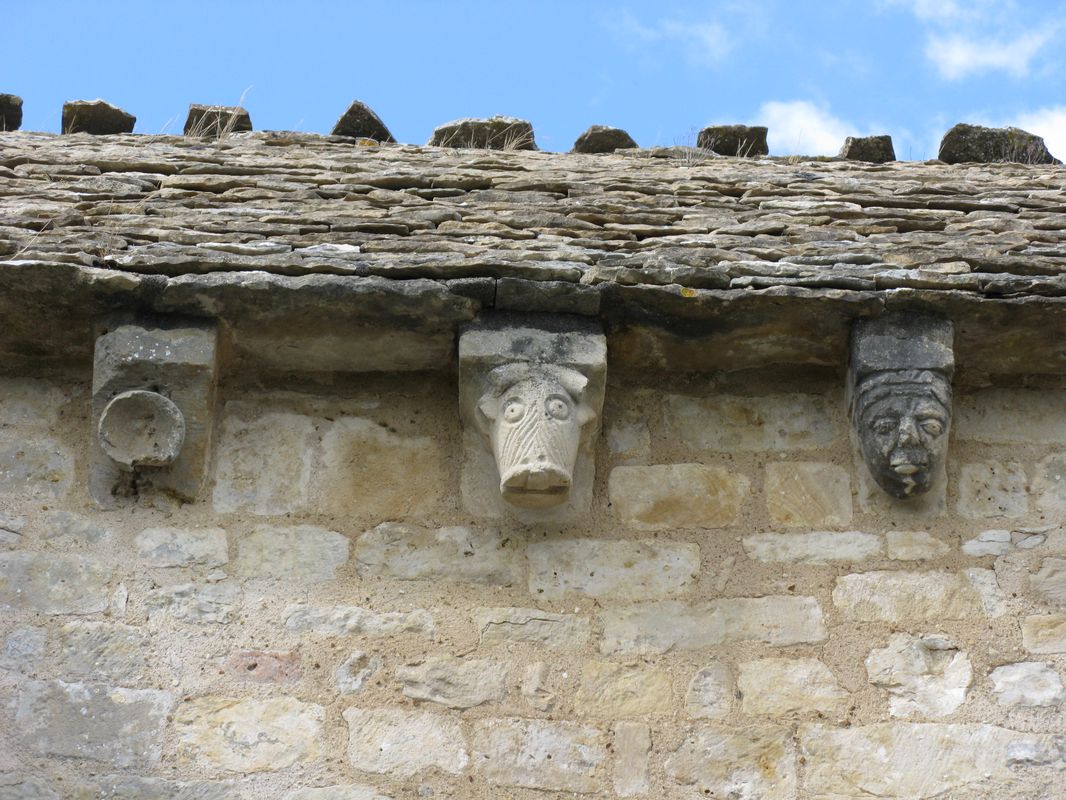 Détail de trois modillons sculptés sur la corniche du mur sud de la nef.