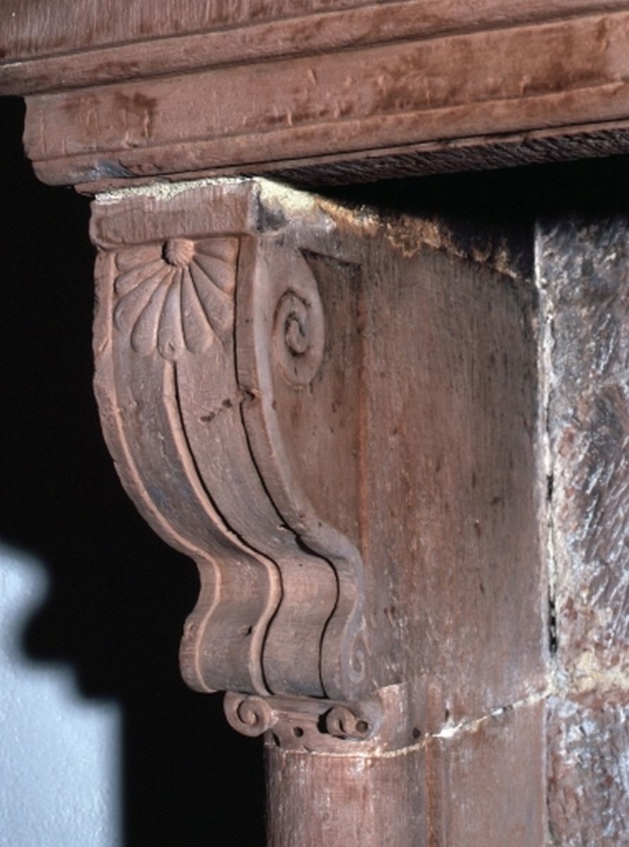 Détail de la console de la cheminée avec une décor de volute rentrante sur les faces latérales et un décor floral sur sa face frontale.
