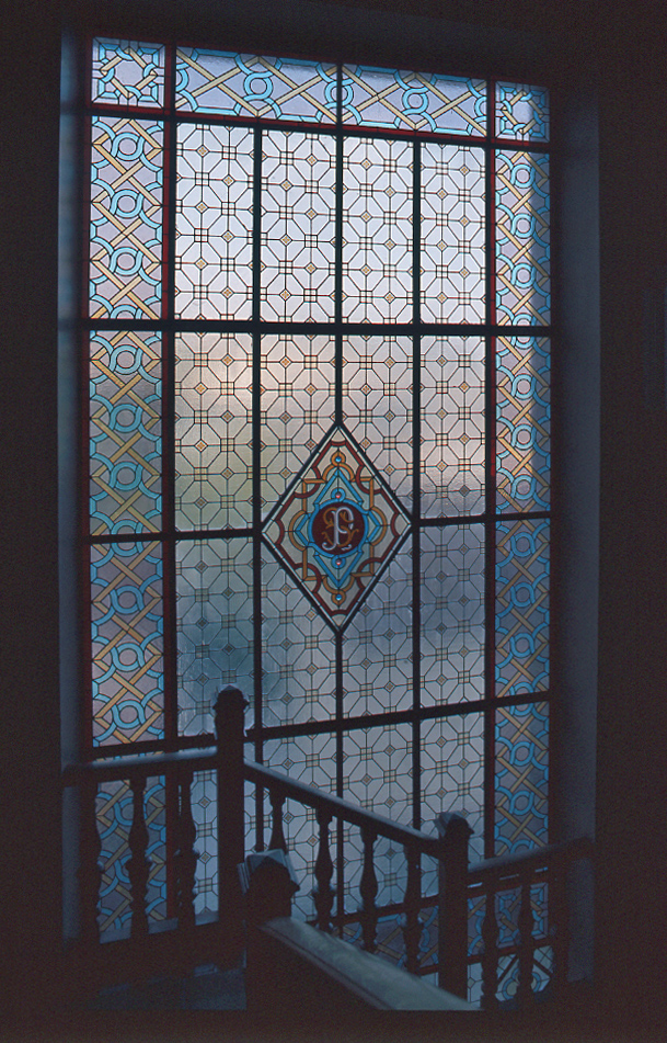 Détail de la verrière mixte à motifs géométriques (vitrerie) agrémentée d'un panneau central héraldique, en forme de losange, portant notamment le S de la famille Sallandrouze.
