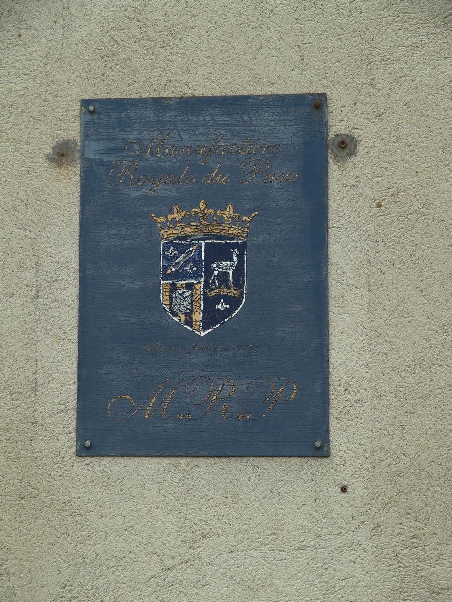 La plaque, à l'entrée de l'usine, portant le nom et le blason de la Manufacture Royale du Parc.