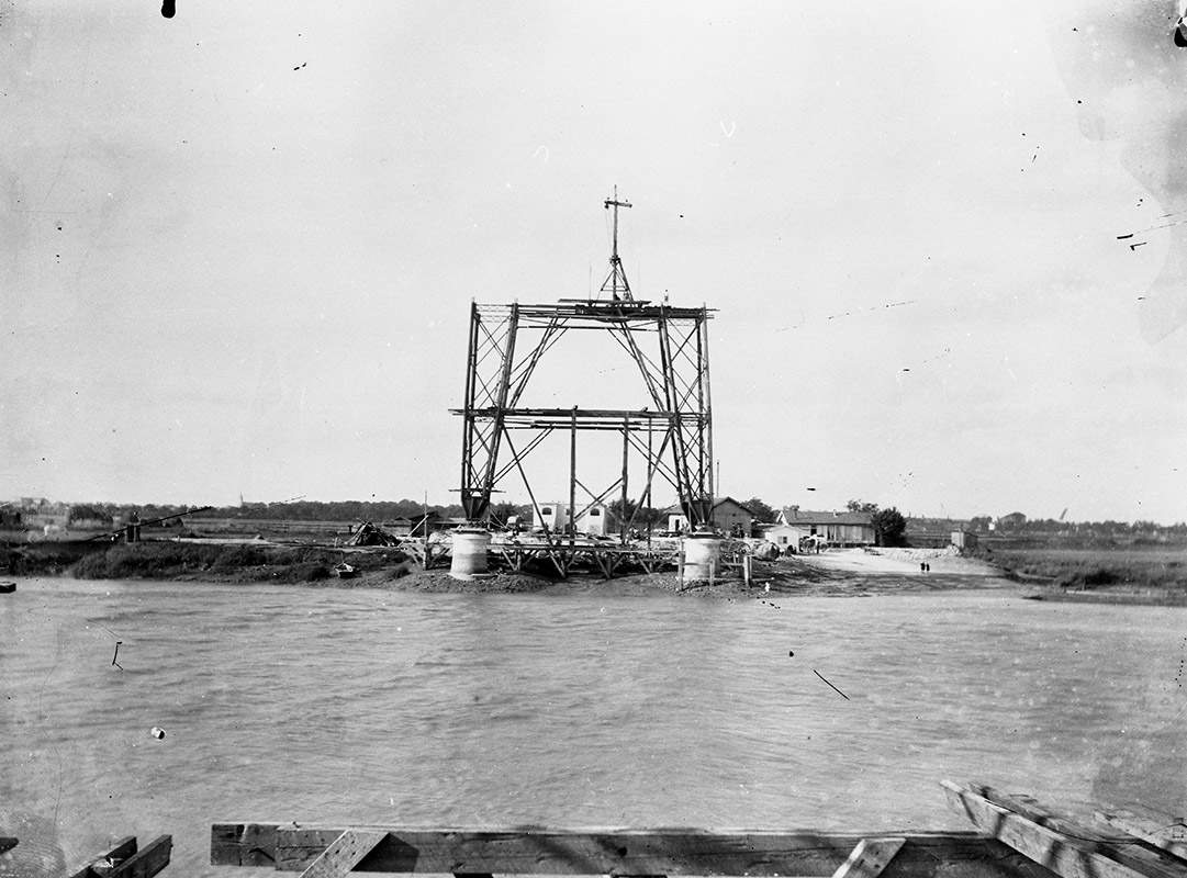 Le pylône de la rive gauche en cours de montage, vu de l'autre rive.