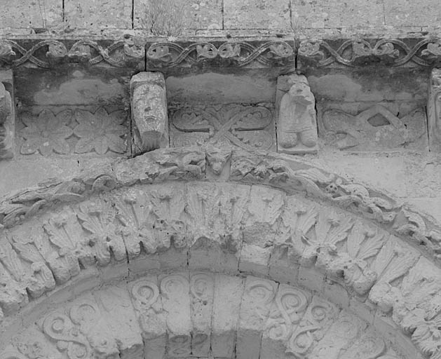 Façade occidentale, corniche supérieure, modillons 7 (tête barbue) et 8 (personnage à genoux) ; métopes 8 (fleurs), 9 (feuilles) et 10 (personnage allongé main sur le bas-ventre).