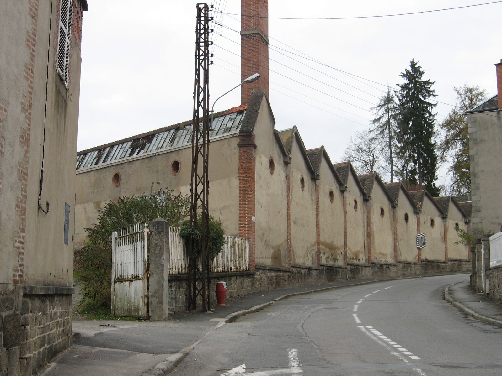 Vue générale des sheds de l'ancienne filature, en direction du sud, vers la chapelle Saint-Jean, avec la courbure des bâtiments épousant celle de la rue