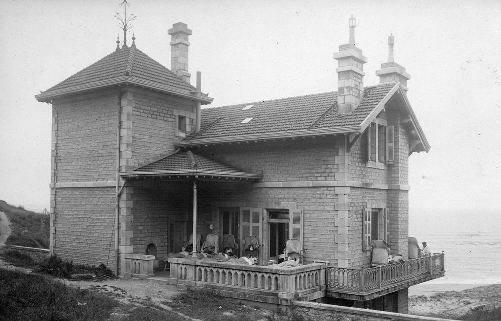Vue de l'ancien bâtiment des cuisines depuis l'est, les malades sont installés sur la terrasse et le balcon filant, 1916-1922.