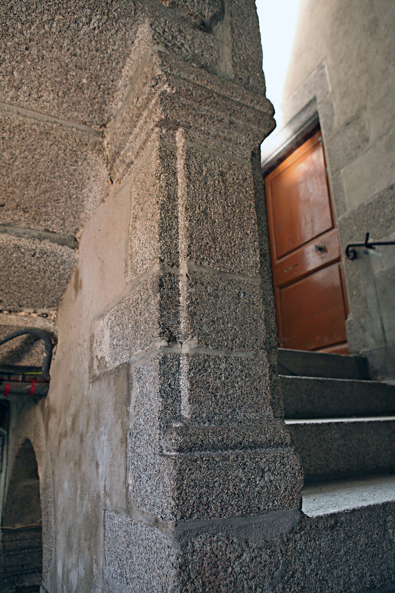 Intérieur de la tour hors-œuvre. Vue partielle, depuis le premier étage, montrant la cage d'escalier en pierre, à volées droites et le mur-noyau