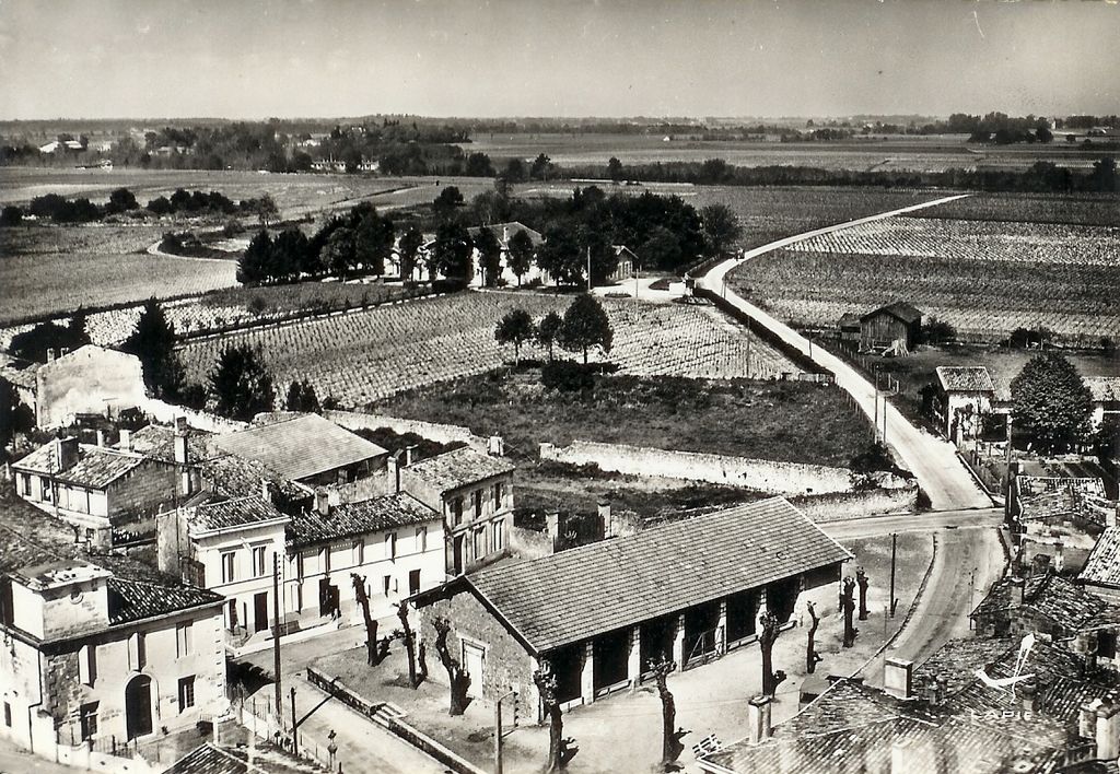 Carte postale (collection particulière) : vue aérienne du village de Beychevelle, place des Joyeusetés avec salle des fêtes, 3e quart 20e siècle.