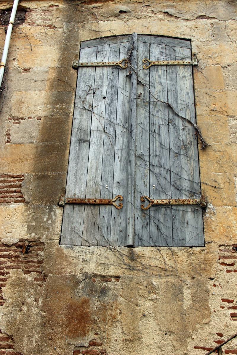 Détail de la façade sur jardin, deuxième travée : fenêtre du rez-de-chaussée surélevé, volets fermés avec pentures en fer forgé.