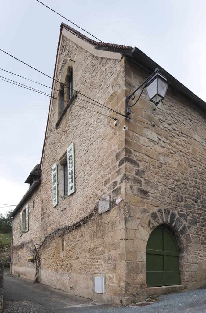 Maison du XIVe siècle de Montignac : vue du mur pignon et du mur gouttereau sur la rue de Versailles ouvert par une porte en arc brisé à longs claveaux.