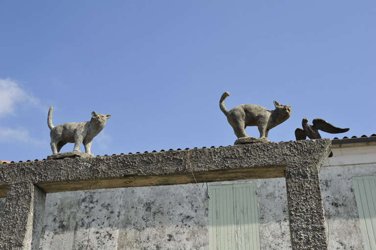 Deux chats et un oiseau perchés sur un portique.