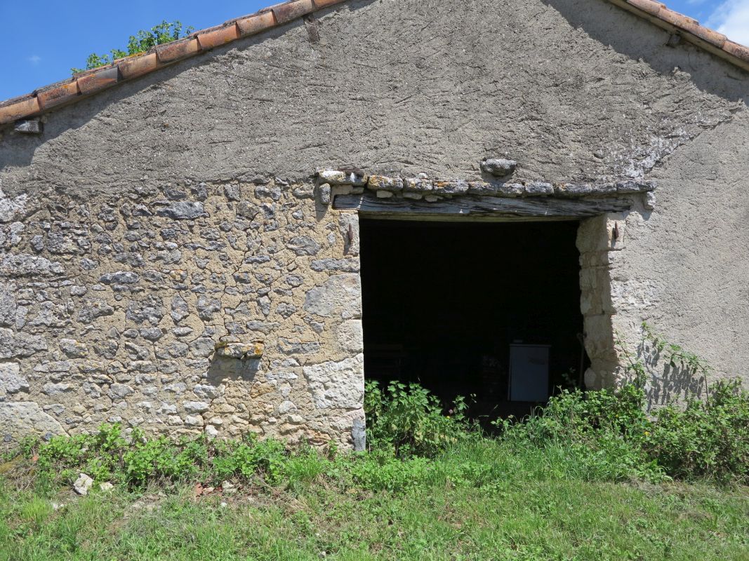 Pignon occidental de la grange, porte charretière avec linteau en bois protégé par un lit de pierres plates et anneau à attacher les bêtes.