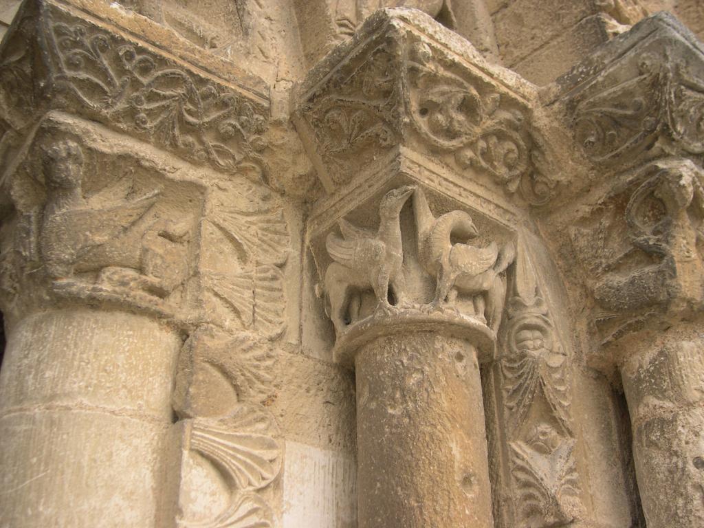Façade occidentale, premier niveau, piédroit droit du portail central, vu de trois quarts. Chapiteau central gauche refait au 19e siècle : griffons.