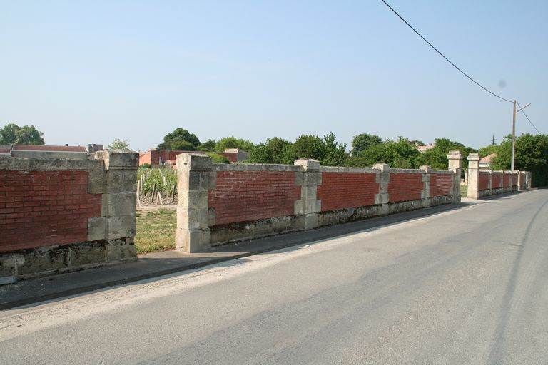 Vue d'un mur de clôture entouré d'une parcelle plantée en vignes.