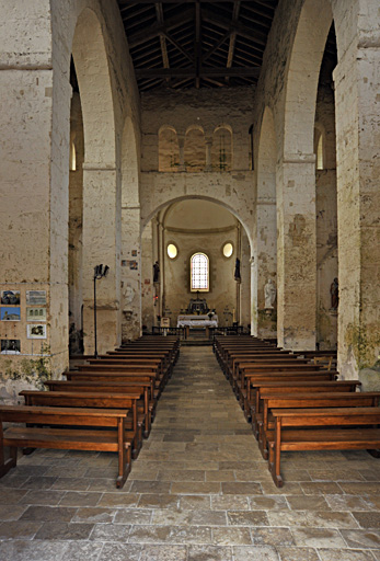 Vue intérieure de la nef de l'église, prise de l'ouest vers le choeur, à l'est. La nef est datée du début du 11e siècle, les grandes arcades de la nef du 13e ou du 14e siècle. Celles-ci divisent la nef en un vaisseau central et deux couloirs latéraux (collatéraux). L'ensemble est charpenté.