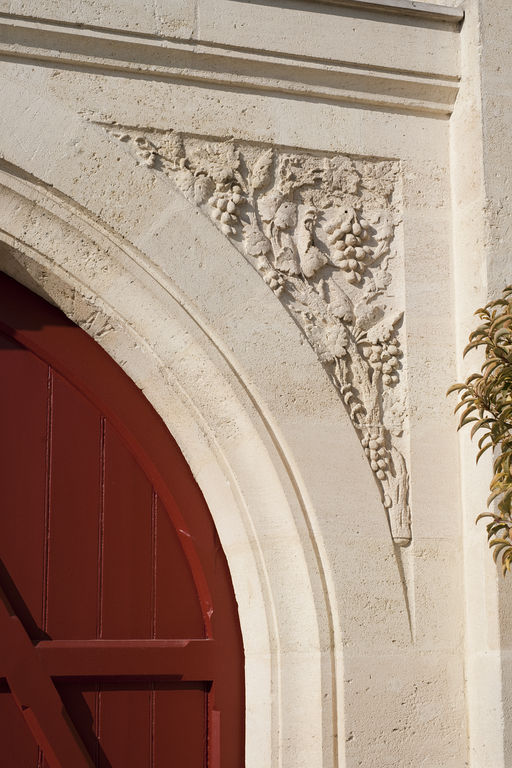 Cuvier, façade-pignon (sud-est) : détail de l'écoinçon de la porte sculpté de motifs de raisin.