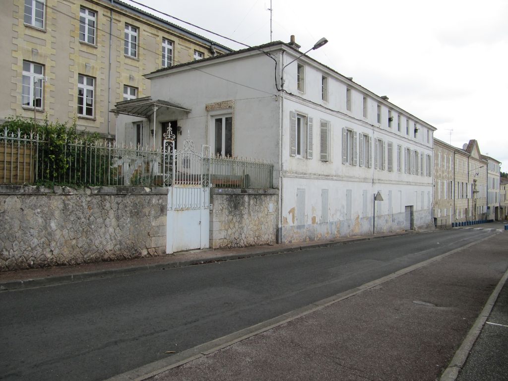 Bâtiments du lycée et maison particulière alignés sur rue.