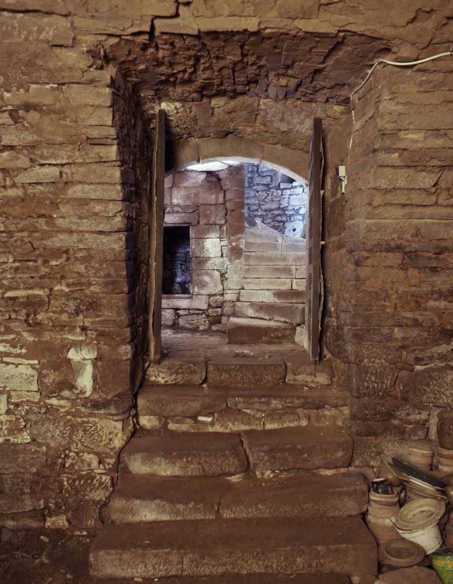 Vue de l'entrée de la cave. On aperçoit le départ de l'escalier en vis tournant à gauche situé dans la tour sud-est ainsi qu'un placard.
