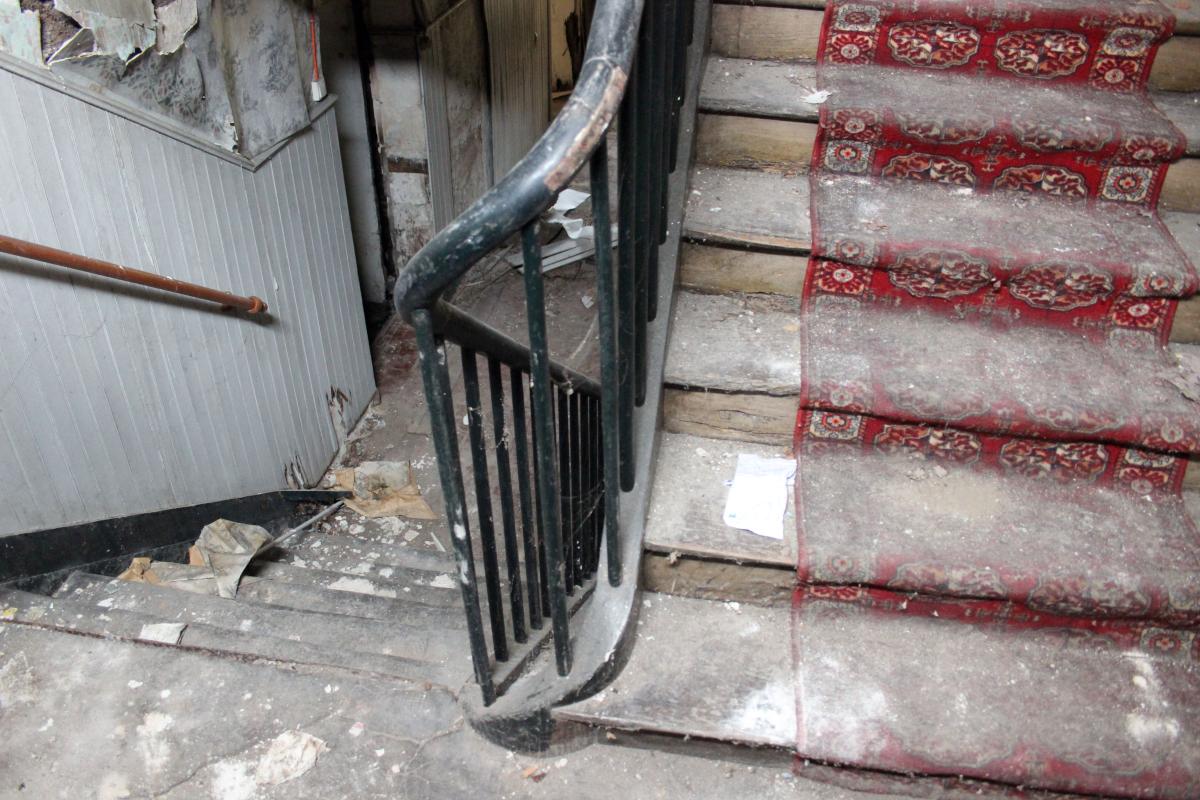 Détail de l'escalier vu depuis la porte d'entrée ; volée descendant au niveau de soubassement.