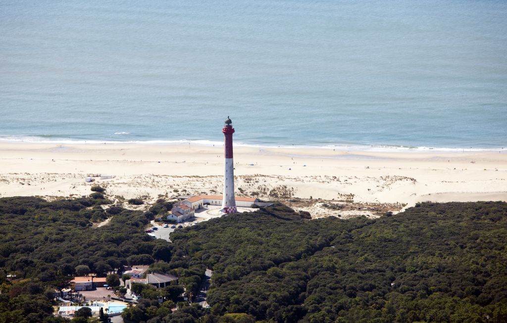 Vue aérienne du phare depuis l'est, à la limite entre forêt et plage.