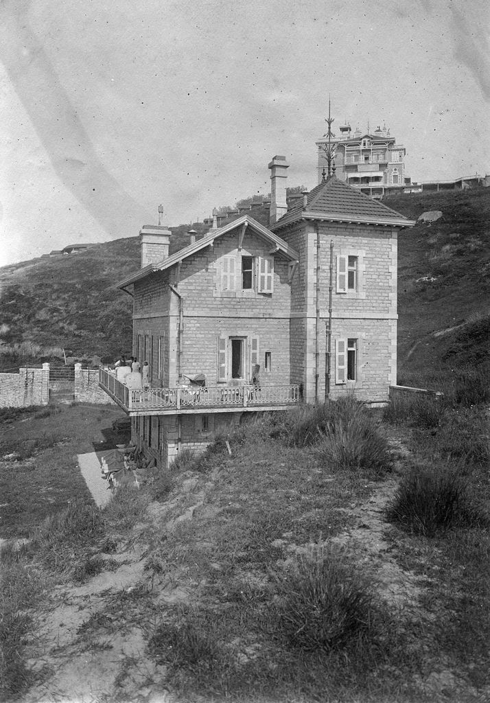 Vue de l'ancien bâtiment des cuisines et des malades installés sur la terrasse et le château en arrière-plan, 1916-1922.. 