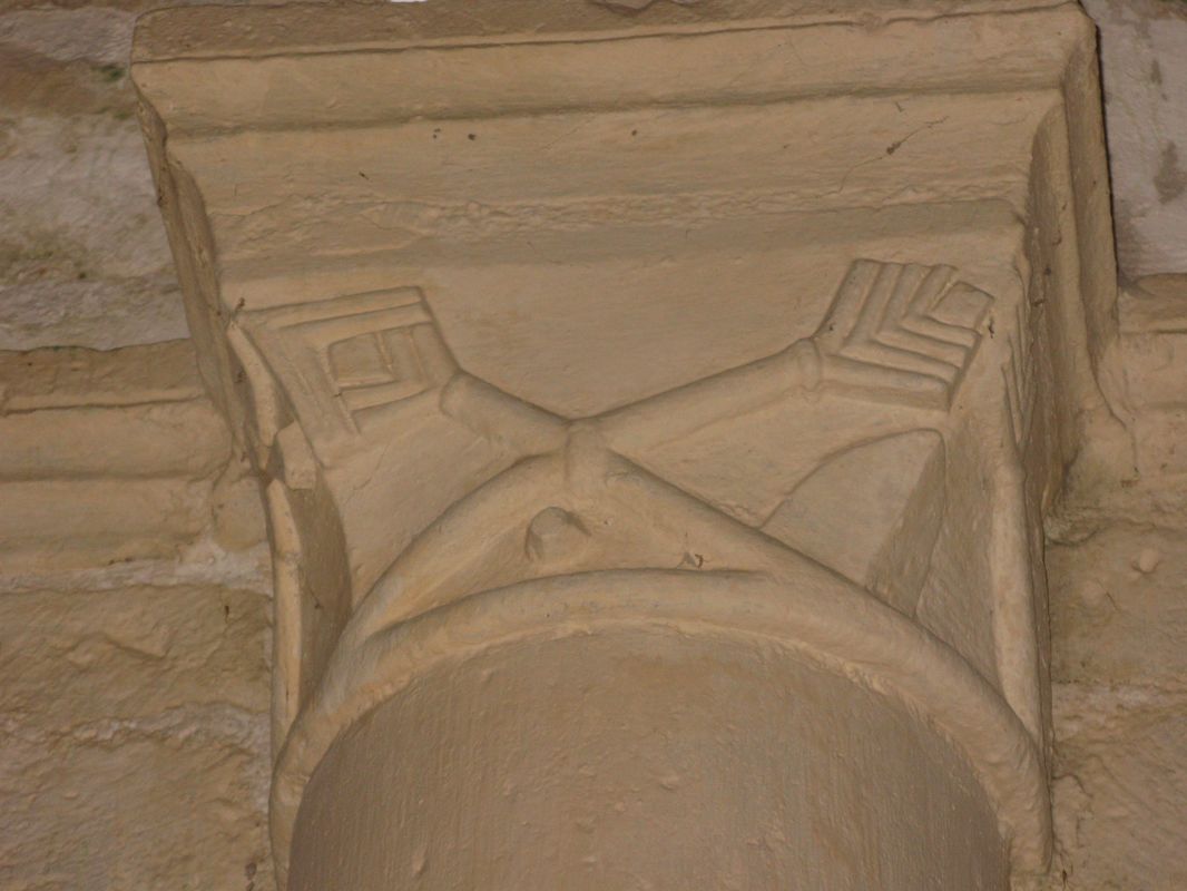 Détail d'un autre chapiteau de la nef : objets entrecroisés pouvant représenter une lance et un rameau feuillagé très stylisé.