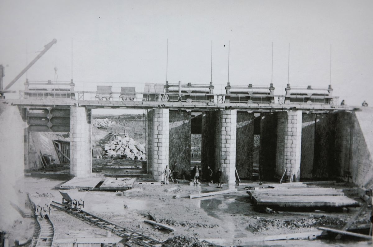 Le barrage en construction vu depuis l'aval en 1929 : les vannes sont montées, les portes de trois pertuis sont en place.