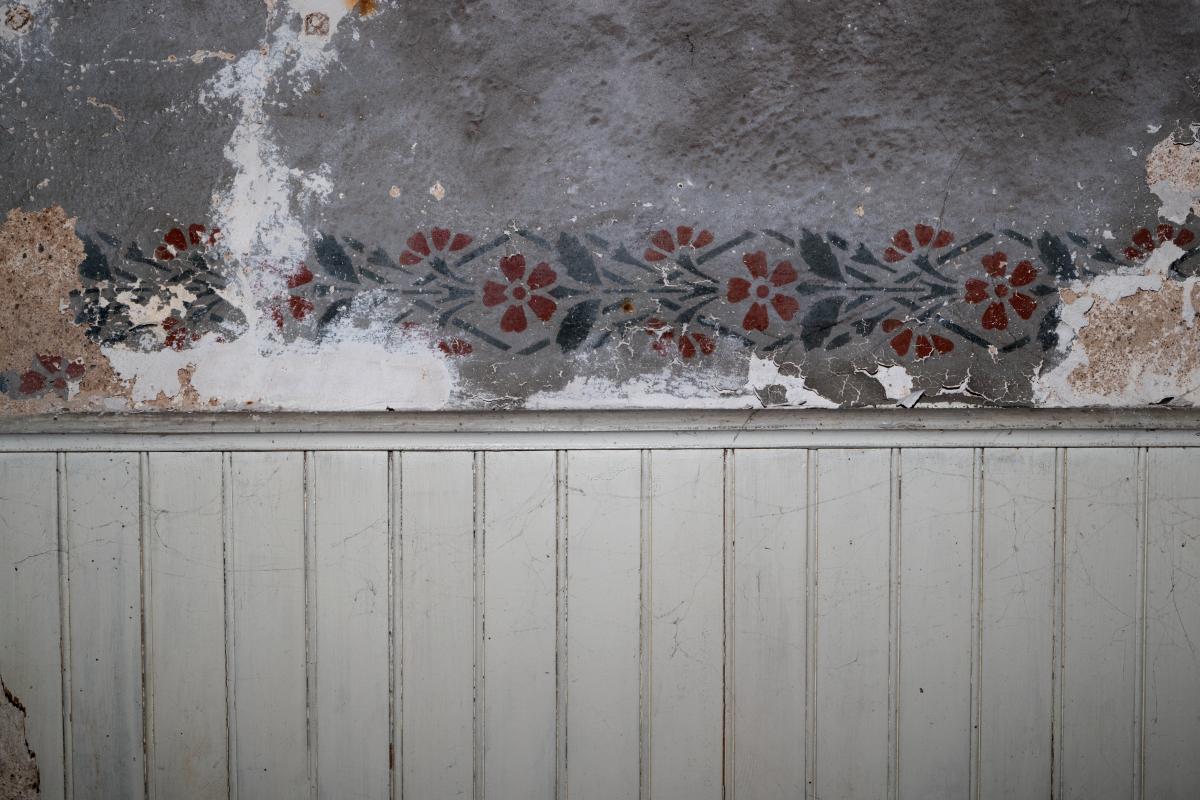 Détail du vestibule axial du niveau de soubassement. Frise peinte au pochoir sur les murs du vestibule, au-dessus du lambris d'appui.