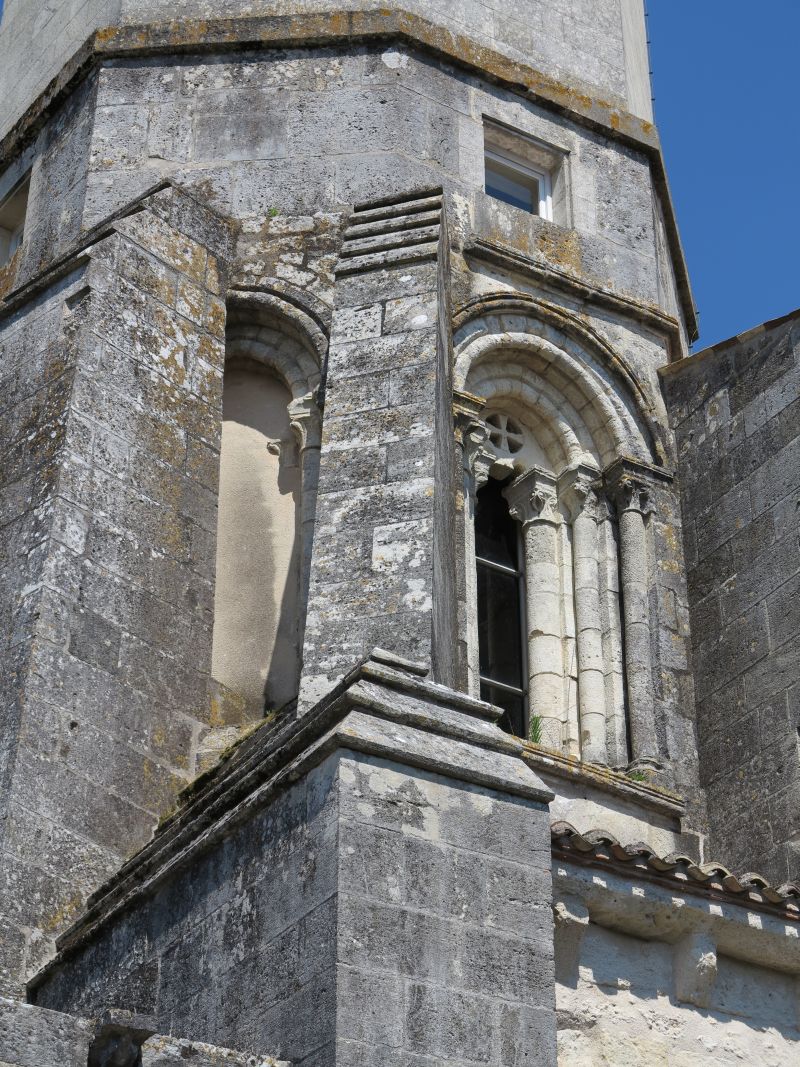 Baies romanes sur la base du clocher, masquées par des contreforts, sous le premier niveau de surélévation du 17e siècle.