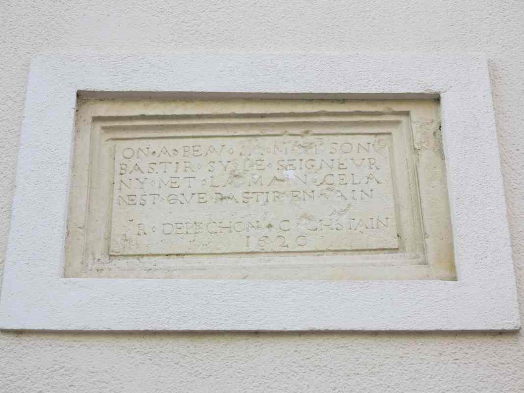 La pierre portant l'inscription, remployée sur la façade d'une maison reconstruite.