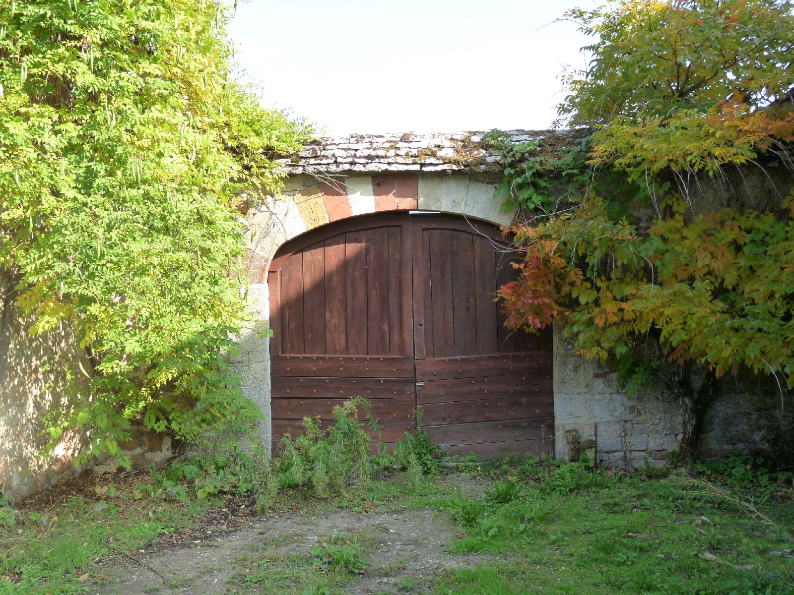Portail en arc en anse-de-panier couvert de lauzes de grès.
