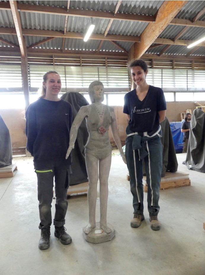 Sculpture de la femme en maillot de bain vert après la première semaine de chantier, encadrée par les deux étudiantes chargées de sa restauration.