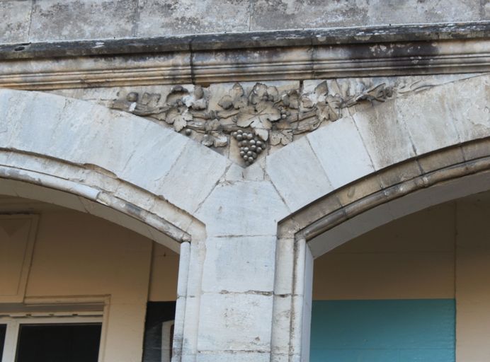 Façade est, galerie : détail du décor sculpté des écoinçons des arcades.