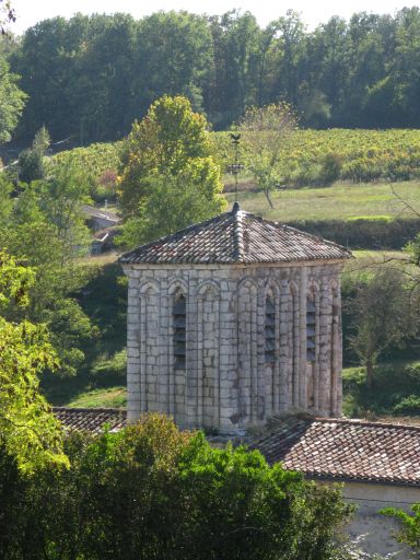 L'église et le bourg dans le vallon dominé par les vignes et les bois.