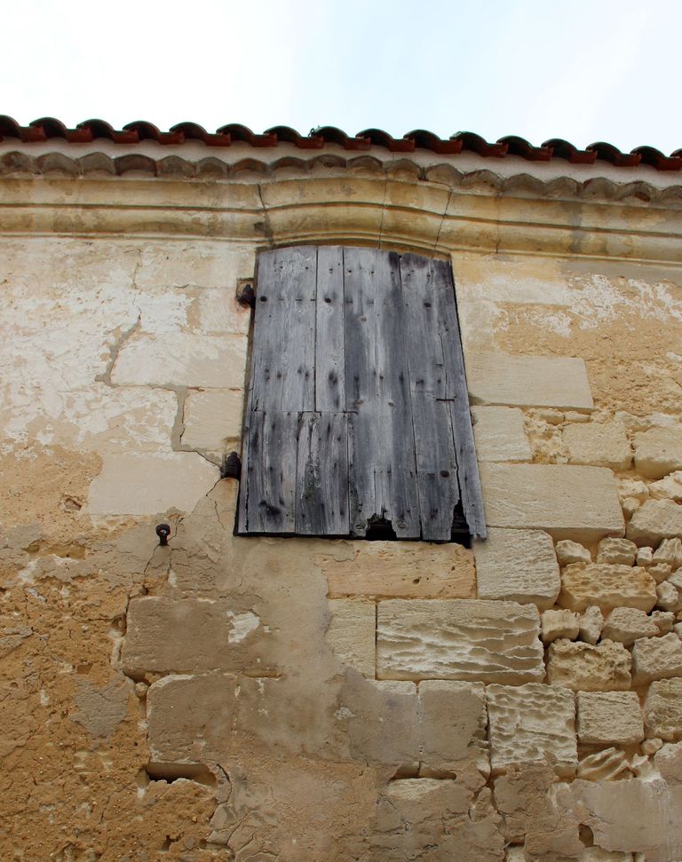 Logis 1, mur gouttereau nord-est : fenêtre en arc segmentaire formant ressaut dans la corniche moulurée.