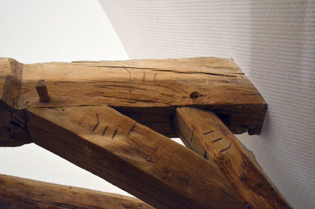 Détail de l'assemblage d'un entrait avec une jambe de force et un aisselier de la charpente du pavillon gauche (nord) : marquage (III) au ciseau à bois répété sur chacune des pièces.